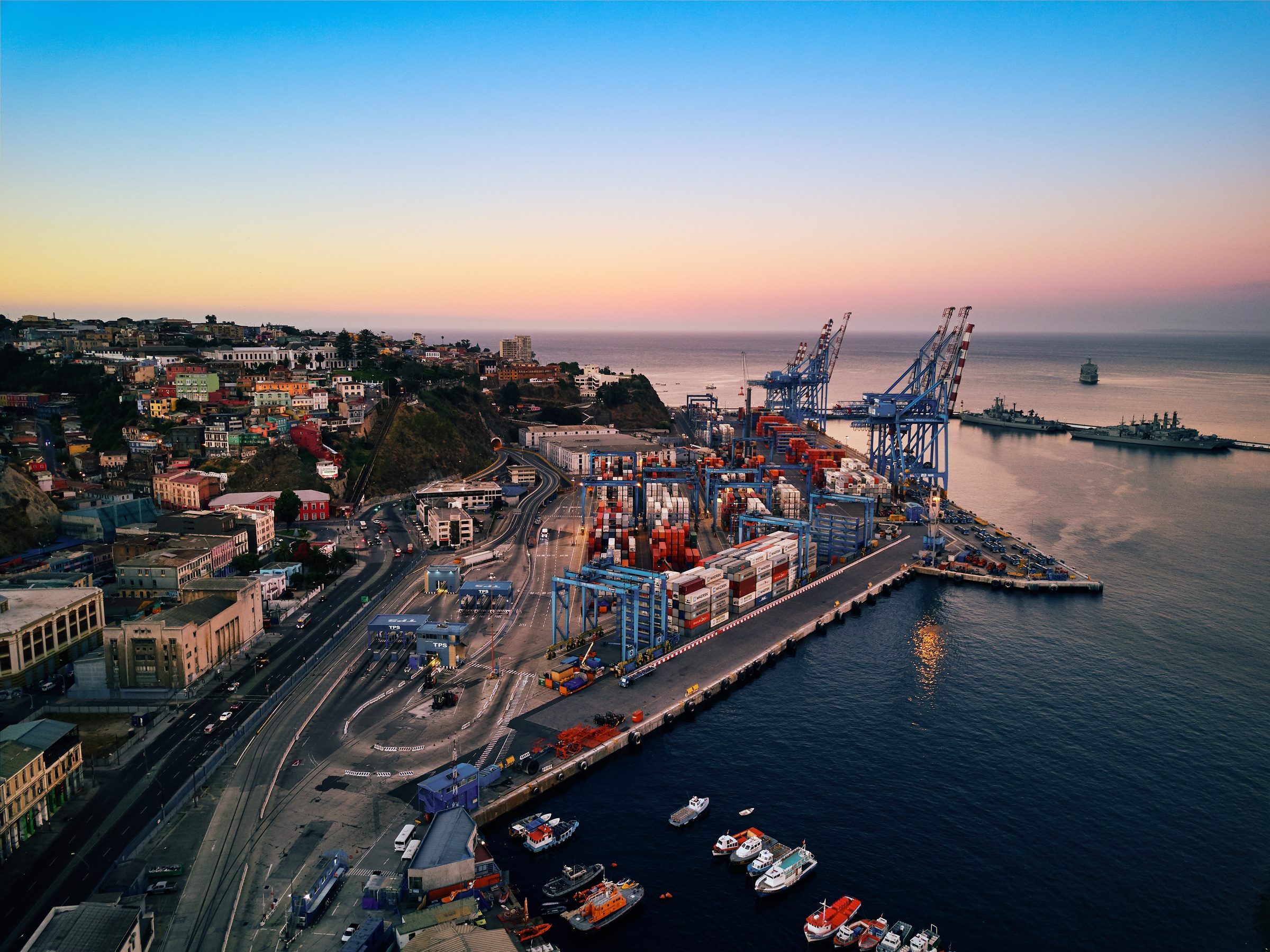 Puerto de Valparaíso al atardecer: espigón con grúas y contenedores, y el mar abierto al horizonte